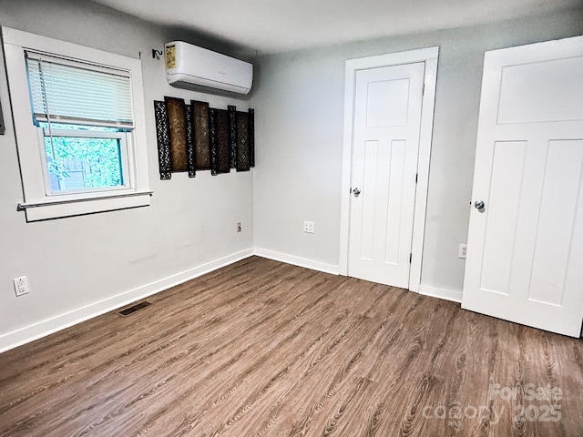 116 N Blue Ridge Ave, Hendersonville, NC 28792 - unfurnished bedroom featuring a wall unit AC, wood finished floors, and baseboards