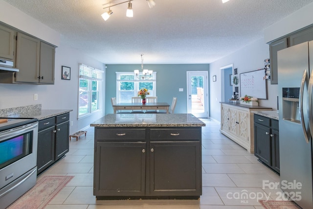 1739 Lesa Lin Dr, Monroe, NC 28112 - kitchen featuring appliances with stainless steel finishes, a kitchen island, healthy amount of natural light, light tile patterned floors, and a textured ceiling