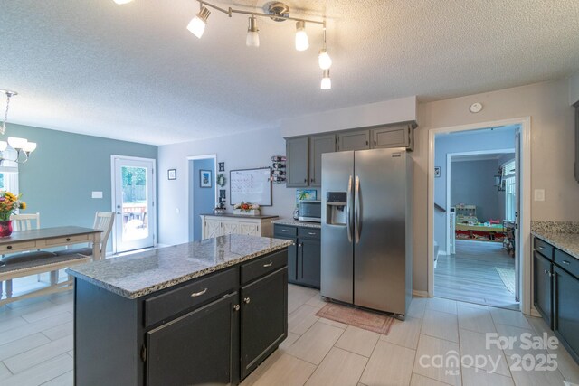 1739 Lesa Lin Dr, Monroe, NC 28112 - kitchen with appliances with stainless steel finishes, a center island, light stone countertops, a textured ceiling, and a chandelier