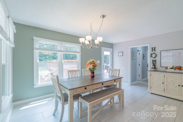 1739 Lesa Lin Dr, Monroe, NC 28112 - dining area featuring a chandelier, a textured ceiling, baseboards, and light tile patterned flooring