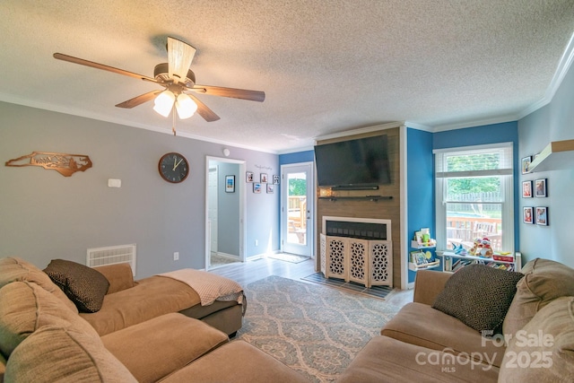 1739 Lesa Lin Dr, Monroe, NC 28112 - living room featuring a fireplace, a textured ceiling, ceiling fan, and crown molding