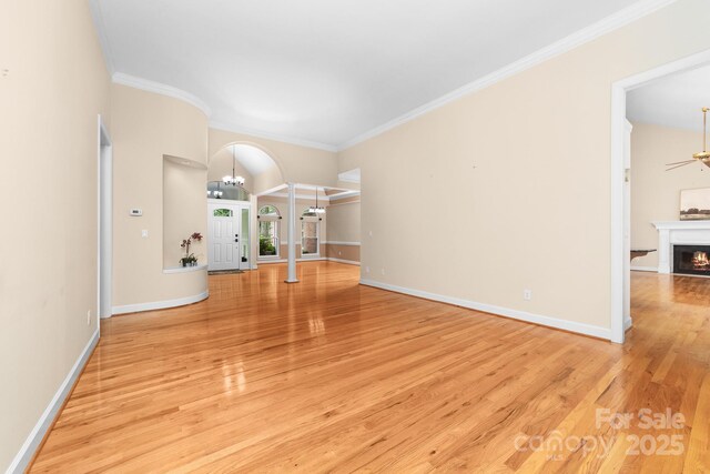 122 Waterford Dr, Mooresville, NC 28117 - unfurnished living room featuring arched walkways, wood finished floors, crown molding, a lit fireplace, and baseboards