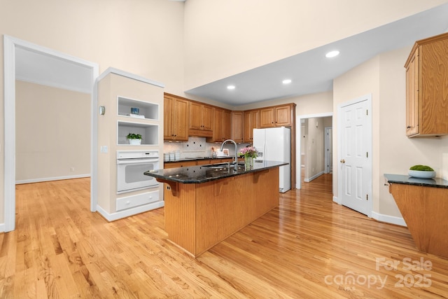 122 Waterford Dr, Mooresville, NC 28117 - kitchen with white appliances, a sink, light wood-style flooring, a breakfast bar, and a towering ceiling