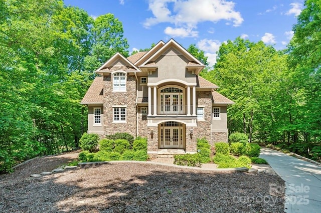 view of front of home featuring french doors, stone siding, and stucco siding