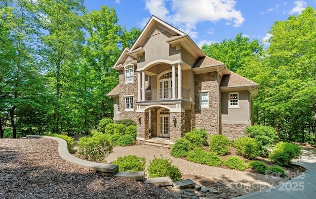 mediterranean / spanish-style house featuring french doors, stone siding, a balcony, and stucco siding