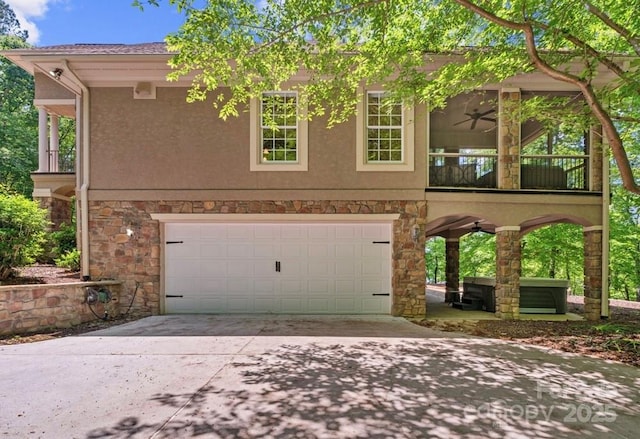 view of front of house with an attached garage, stone siding, concrete driveway, stucco siding, and a ceiling fan