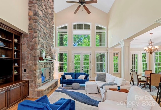 living area featuring high vaulted ceiling, a chandelier, ceiling fan, french doors, and a fireplace