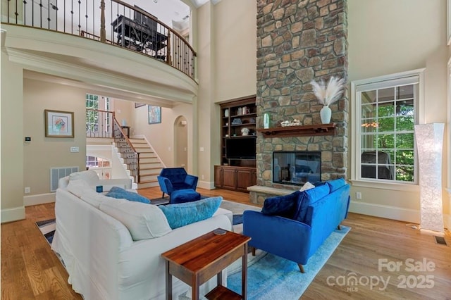 living area featuring stairs, baseboards, wood finished floors, healthy amount of natural light, and a high ceiling