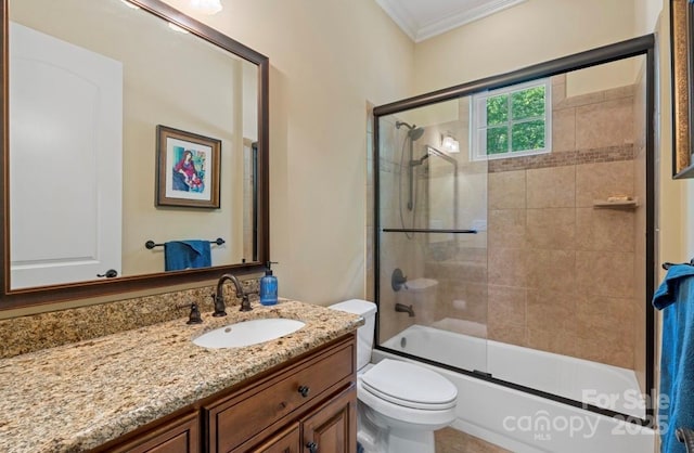 bathroom featuring ornamental molding, toilet, vanity, and bath / shower combo with glass door