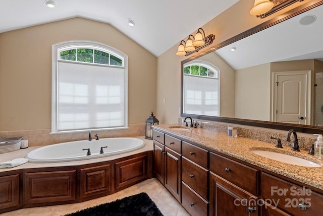 full bathroom featuring vaulted ceiling, healthy amount of natural light, a garden tub, double vanity, and tile patterned floors