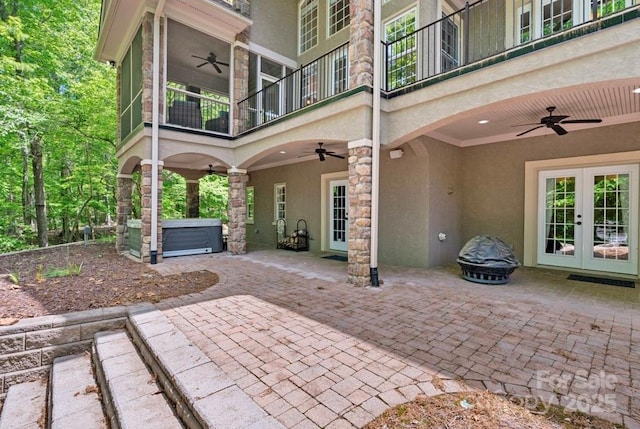 view of patio featuring a ceiling fan, french doors, a hot tub, and a balcony