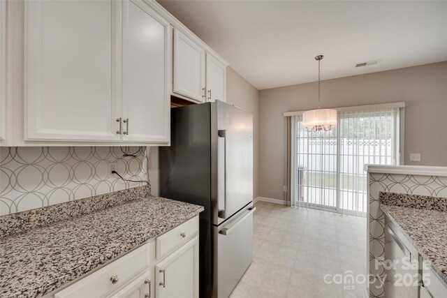 2169 Shady Pond Dr, Clover, SC 29710 - kitchen featuring freestanding refrigerator, white cabinetry, a chandelier, light stone countertops, and pendant lighting