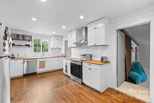 2536 Bancroft St, Charlotte, NC 28206 - kitchen with appliances with stainless steel finishes, wooden counters, wall chimney exhaust hood, a sink, and dark wood-style floors