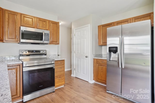 6332 Sackett Way, Charlotte, NC 28269 - kitchen with appliances with stainless steel finishes, light wood-style flooring, brown cabinets, and light stone counters