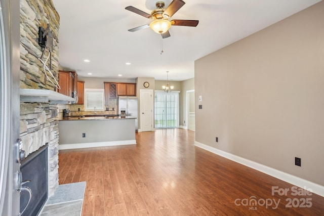 2021 Chantilly Ln, Salisbury, NC 28146 - unfurnished living room with a stone fireplace, a chandelier, light wood-style floors, a ceiling fan, and baseboards