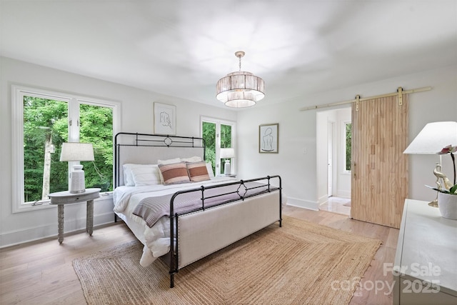 9520 Squirrel Hollow Ln, Charlotte, NC 28270 - bedroom featuring a barn door, multiple windows, and light wood-style flooring