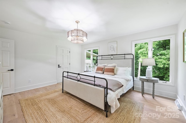 9520 Squirrel Hollow Ln, Charlotte, NC 28270 - bedroom featuring light wood-type flooring, a chandelier, multiple windows, and baseboards