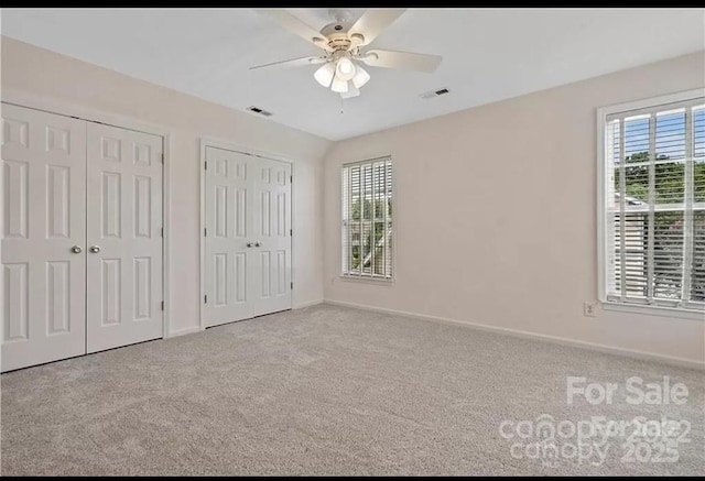unfurnished bedroom with multiple closets, carpet, and multiple windows