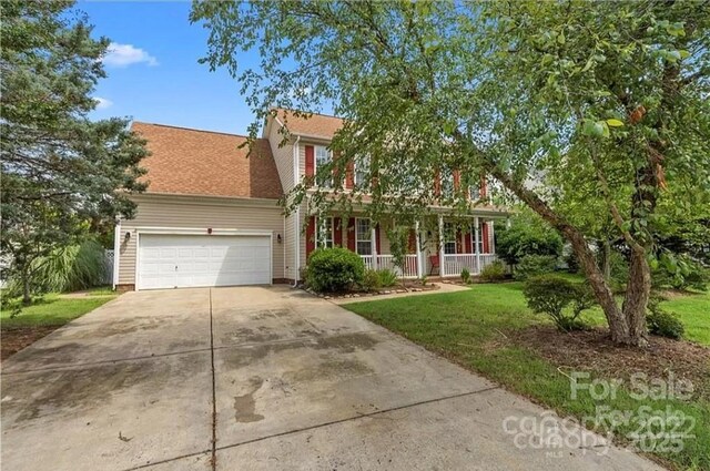 view of front of house with a porch, driveway, an attached garage, and a front lawn