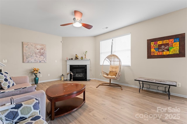 1911 Savannah Hills Dr, Matthews, NC 28105 - living room with light wood-style flooring, a ceiling fan, a fireplace with flush hearth, and baseboards