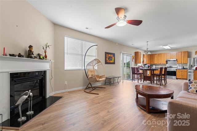 1911 Savannah Hills Dr, Matthews, NC 28105 - living area featuring a ceiling fan, light wood-style flooring, a glass covered fireplace, and baseboards