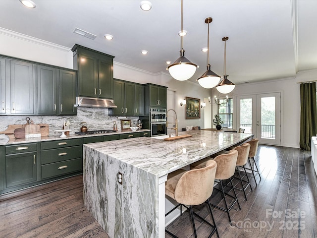 121 Enclave Meadows Ln, Matthews, NC 28104 - kitchen featuring under cabinet range hood, green cabinets, crown molding, appliances with stainless steel finishes, and dark wood-style flooring