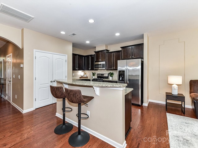 7325 Overmountain Dr, Rock Hill, SC 29732 - kitchen featuring appliances with stainless steel finishes, arched walkways, a breakfast bar area, dark wood-type flooring, and light stone counters