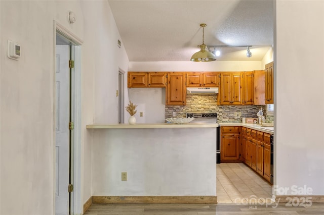 2011 20th Street Pl NE, Hickory, NC 28601 - kitchen featuring under cabinet range hood, electric range, light countertops, backsplash, and brown cabinetry