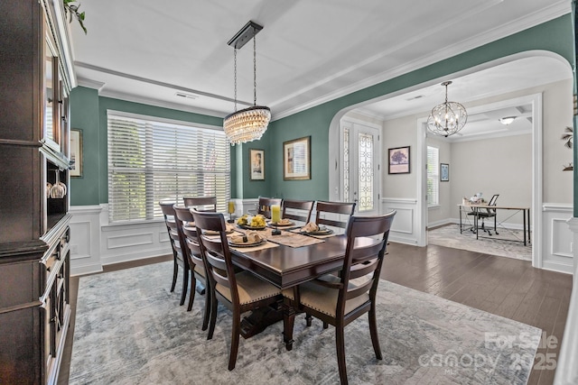 2414 Madeira Cir, Waxhaw, NC 28173 - dining space with arched walkways, a chandelier, crown molding, a wainscoted wall, and dark wood-style floors