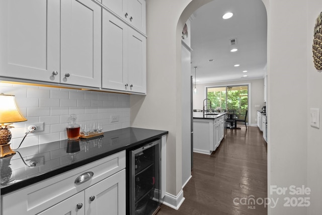 2414 Madeira Cir, Waxhaw, NC 28173 - indoor dry bar with beverage cooler, dark wood-style floors, tasteful backsplash, arched walkways, and baseboards