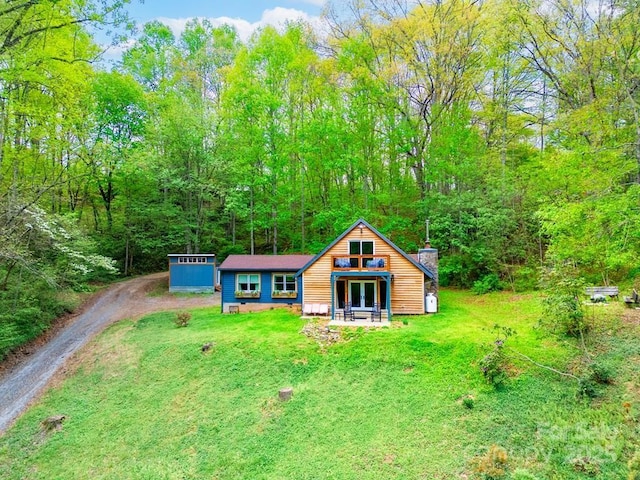 406 Poker Branch Rd, Sylva, NC 28779 - view of front of home with dirt driveway, a front yard, a forest view, french doors, and a chimney