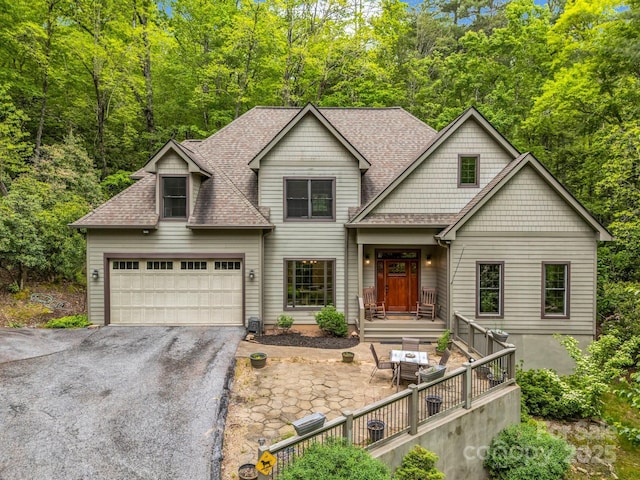 view of front of house featuring roof with shingles and asphalt driveway