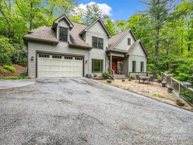 view of front of house featuring roof with shingles, driveway, cooling unit, and a garage