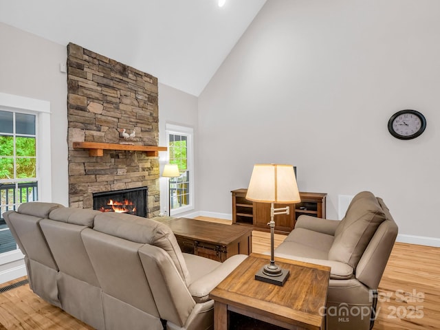 living area with high vaulted ceiling, light wood-style floors, baseboards, and plenty of natural light