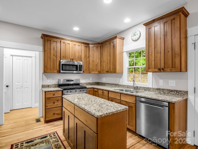 kitchen featuring appliances with stainless steel finishes, a sink, light wood-style floors, light stone countertops, and recessed lighting
