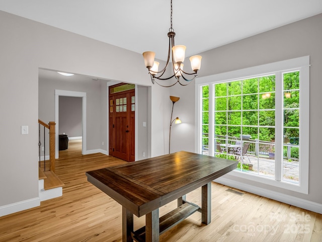 dining space with baseboards, light wood-style flooring, and a chandelier