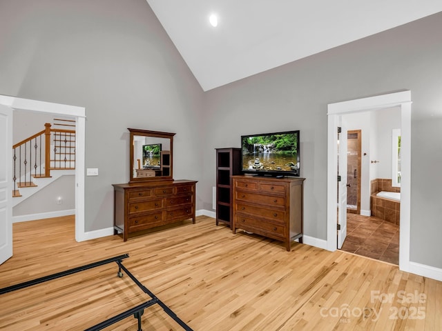 bedroom featuring light wood-style flooring, high vaulted ceiling, and baseboards