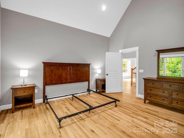 bedroom featuring high vaulted ceiling, light wood finished floors, and baseboards
