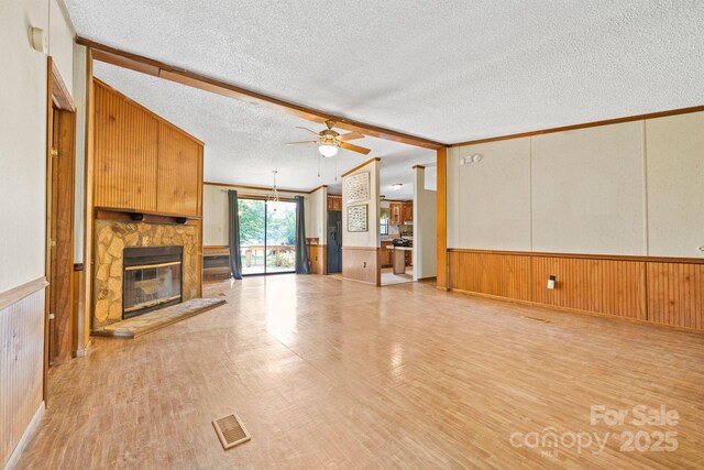 6822 Zelda Dr, Catawba, NC 28609 - unfurnished living room with a ceiling fan, light wood-style flooring, a textured ceiling, a wainscoted wall, and a stone fireplace