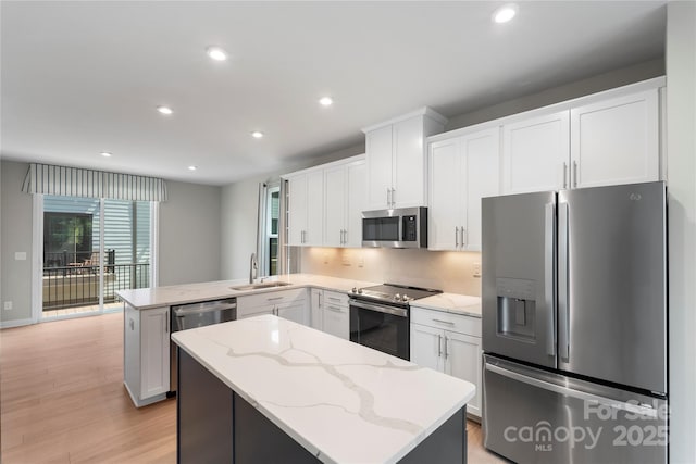 kitchen with stainless steel appliances, a sink, a peninsula, a kitchen island, and recessed lighting