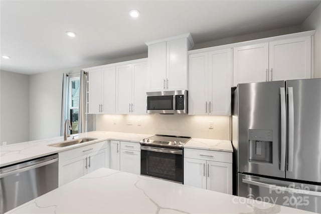 kitchen featuring appliances with stainless steel finishes, a sink, white cabinetry, and recessed lighting