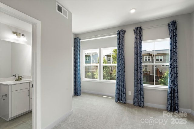 spare room with a sink, baseboards, and light carpet