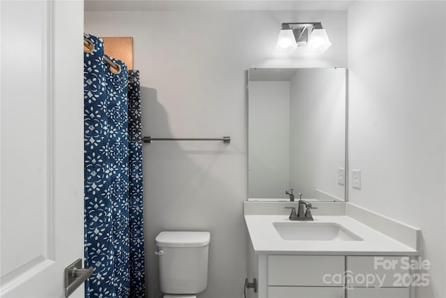 bathroom featuring toilet, vanity, and a shower with curtain