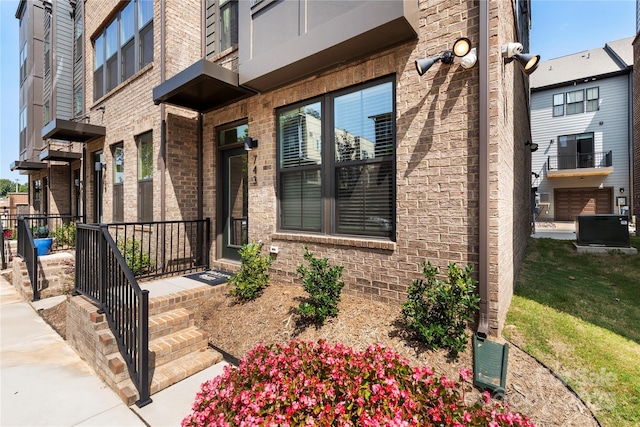 view of exterior entry featuring central AC, brick siding, and a surveillance system