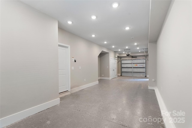 unfurnished living room with baseboards, recessed lighting, a garage, and concrete flooring