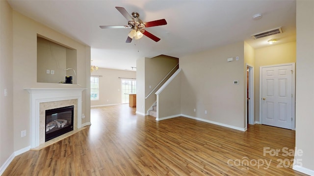 12222 Stratfield Place Cir, Pineville, NC 28134 - unfurnished living room featuring wood finished floors, a ceiling fan, a premium fireplace, stairway, and baseboards