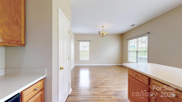 12222 Stratfield Place Cir, Pineville, NC 28134 - kitchen with light wood-type flooring, a chandelier, light countertops, baseboards, and brown cabinets