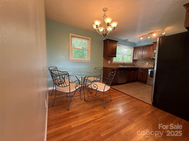 1303 Rambling Acres Cir, Lenoir, NC 28645 - kitchen featuring appliances with stainless steel finishes, light wood-style floors, a chandelier, decorative backsplash, and a textured ceiling