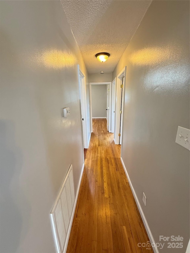 1303 Rambling Acres Cir, Lenoir, NC 28645 - hallway featuring a textured ceiling, baseboards, and wood-type flooring