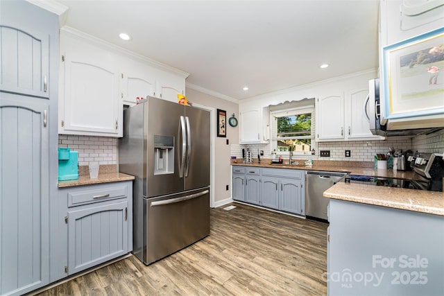 2401 Hoffman St, Gastonia, NC 28054 - kitchen featuring stainless steel appliances, wood finished floors, ornamental molding, tasteful backsplash, and white cabinets